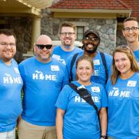 Alumni pose in front of the Alumni House